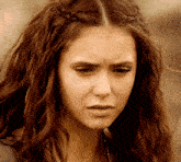a close up of a woman 's face with her hair in a braid