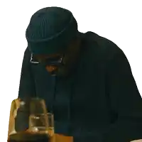 a man wearing a blue beanie and glasses looks down at something