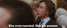 a man in a suit and tie is talking to a woman in a crowd .