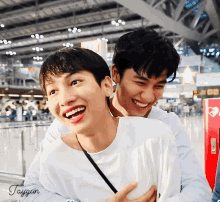 two young men are hugging each other and one of them has taygun written on the bottom of his shirt