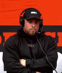 a man wearing headphones and a hat is sitting in front of a microphone .