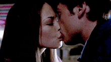 a man and a woman are kissing in front of a pink wall