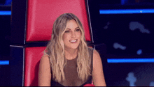 a woman in a black dress is sitting in a red chair smiling