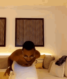 a shirtless man is doing push ups in a living room with a couch .