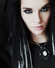a close up of a person 's face with black hair and a necklace