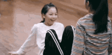 two young girls are sitting on a wooden floor and laughing .