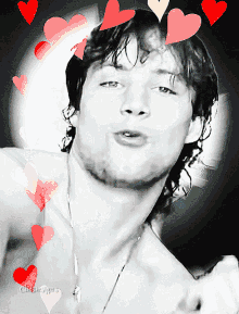 a black and white photo of a shirtless man with hearts around his face