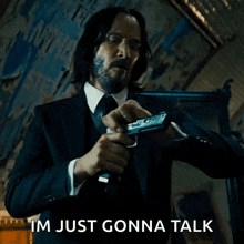 a man in a suit and tie is holding a gun and says i 'm just gonna talk