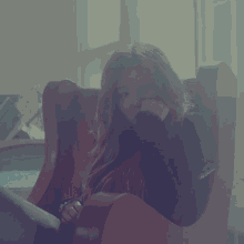 a woman is sitting in a red chair with her hand on her chin