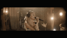 a woman wearing headphones sings into a microphone on a stage