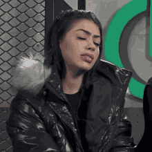 a woman wearing a black jacket with a fur hood making a funny face