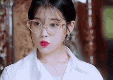 a woman wearing glasses and a white shirt is looking at the camera