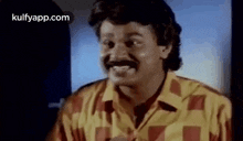 a man with a mustache is smiling in a yellow and red shirt .