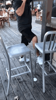 a man squatting on a chair on a deck