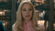 a woman with blonde hair is wearing a pink dress