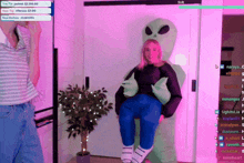 a woman is sitting in front of an alien costume