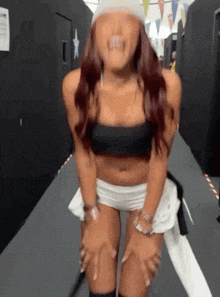 a woman in a crop top and shorts is standing on a hallway .