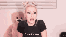a woman is standing next to a teddy bear and talking .