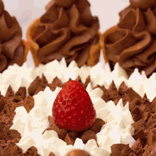 a strawberry sits on top of a chocolate cake