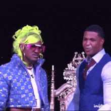 two men are standing next to each other with one wearing neon green hair and sunglasses