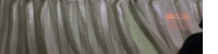 a person is standing in front of a window with a sheer curtain .