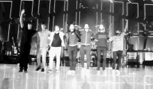 a group of men are standing on a stage with their hands in the air