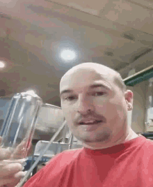 a bald man with a beard and mustache is wearing a red shirt and smiling