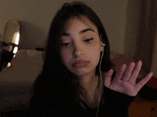 a woman wearing ear buds and a black shirt shows her middle finger