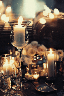 a wine glass with a lit candle in it sits on a table with other candles