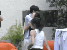 a man is carrying a woman in his arms and they are kissing