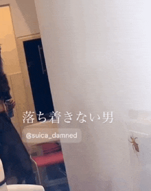 a woman standing in front of a white wall with a spider on it and the words suica_damned on the bottom