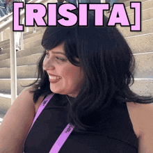 a woman wearing a black top and a purple lanyard with the word irisita