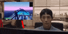 a man is sitting in front of a computer monitor with a game on it .
