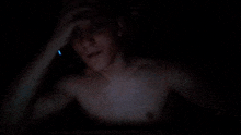 a shirtless man is talking on a phone in the dark