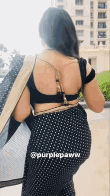 the back of a woman wearing a black and gold polka dot saree .