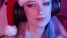 a woman wearing headphones and a santa hat is sitting in front of a computer .