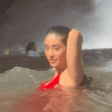 a woman in a red bikini is swimming in the ocean