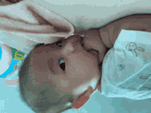 a baby is laying on a bed with a towel covering his head