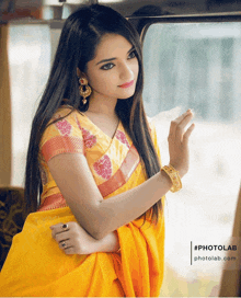 a woman in a yellow saree is looking out of a car window with a photolab.com logo in the corner