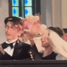 a man in a tuxedo is holding a bouquet of flowers in front of a woman in a wedding dress .