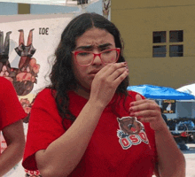 a woman wearing glasses and a red shirt that says oso