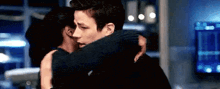 a man and a woman are hugging in a room .