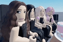 a group of girls are sitting in a row with a cake in the background