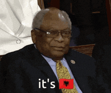 a man in a suit and tie says it 's while holding an albanian flag