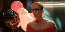 a woman in a red dress is standing in front of balloons that say bachelorette party .