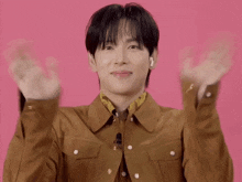 a young man in a brown jacket is making a face with his hands