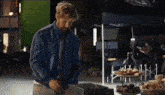 a man in a blue jacket and tie is standing in front of a table with food on it