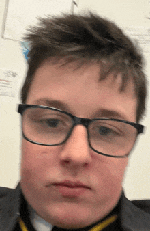 a young boy wearing glasses and a black jacket looks at the camera