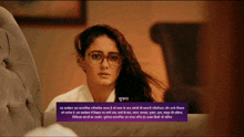 a woman wearing glasses and a white shirt has a purple box below her that says ' suryana ' on it
