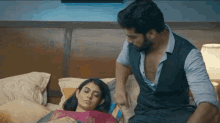 a man and a woman are sitting on a bed and the woman is laying on the man 's lap .